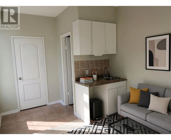 A living room with a grey couch and a kitchenette.