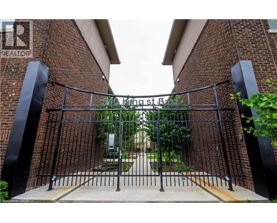 A black metal gate with a brick wall on either side.