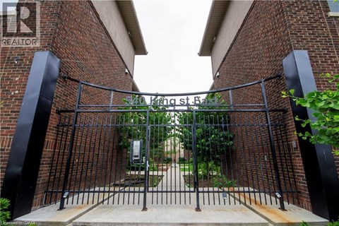 A black metal gate with a brick wall on either side.