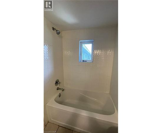 A white bathtub in a bathroom with a window above it.