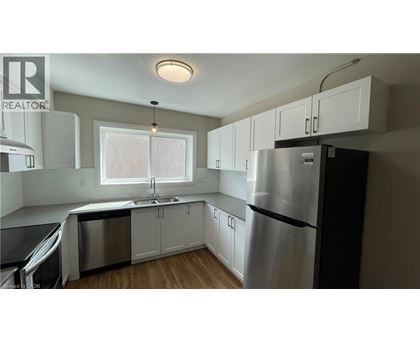 A kitchen with white cabinets and a stainless steel refrigerator.