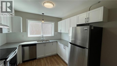 A kitchen with white cabinets and a stainless steel refrigerator.