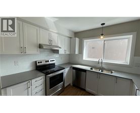 A kitchen with white cabinets and a stove top oven.