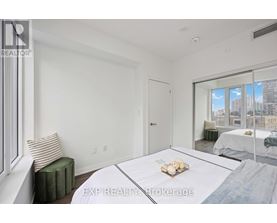 A bedroom with a large bed and a window overlooking a cityscape.
