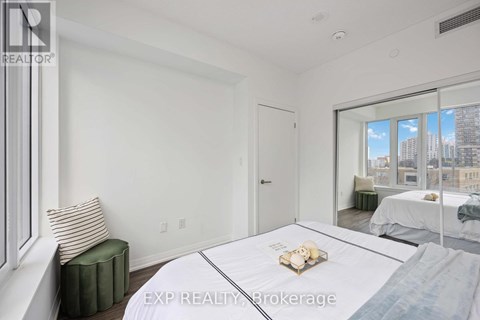 A bedroom with a large bed and a window overlooking a cityscape.