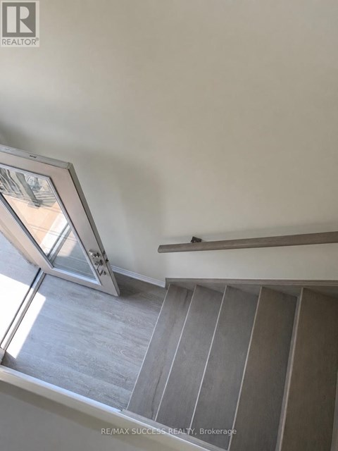 A staircase with a glass door and a wooden handrail.