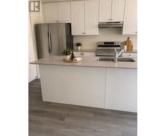 A kitchen with white cabinets and a stainless steel refrigerator.