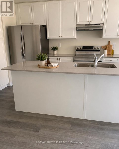 A kitchen with white cabinets and a stainless steel refrigerator.