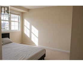 A bedroom with a bed and a window letting in sunlight.