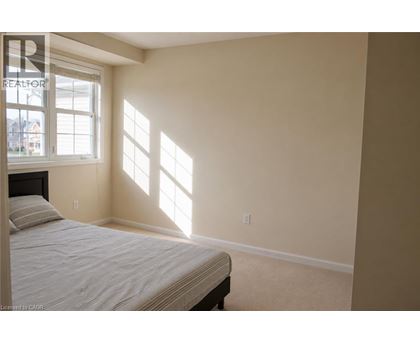 A bedroom with a bed and a window letting in sunlight.