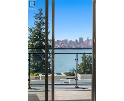 A view of a city skyline through a window with a tree in the foreground.