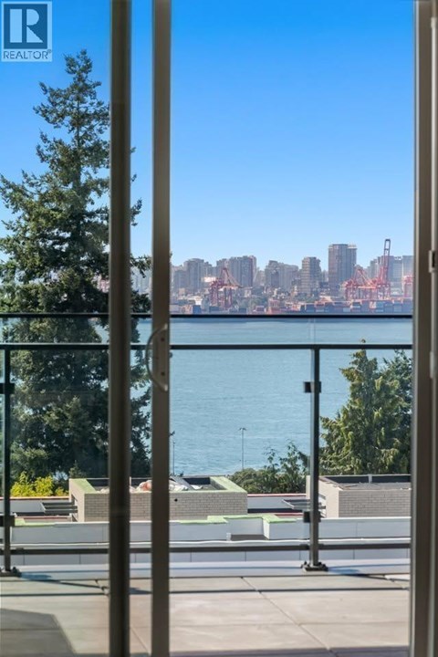 A view of a city skyline through a window with a tree in the foreground.
