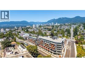 A cityscape with a mountain range in the background and a building with the logo "REALTOR" on the top left corner.
