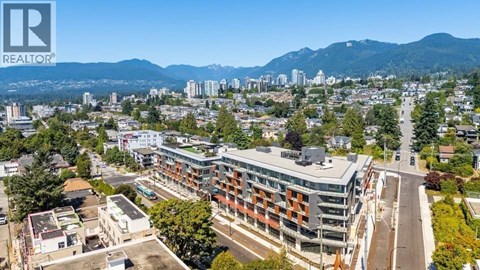 A cityscape with a mountain range in the background and a building with the logo "REALTOR" on the top left corner.