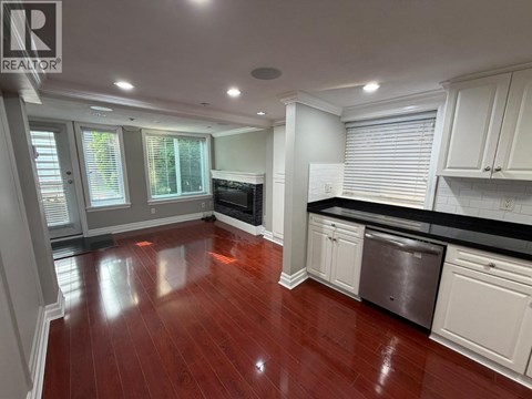 A kitchen with white cabinets and a wooden floor.