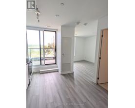 A spacious room with wooden flooring and a large window overlooking a balcony.