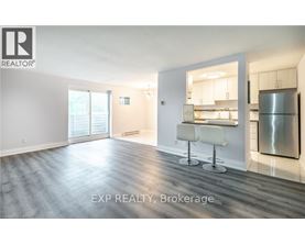 A spacious room with a kitchenette in the background.