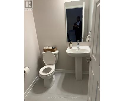 A man is reflected in a bathroom mirror.
