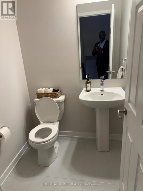 A man is reflected in a bathroom mirror.