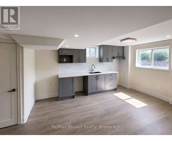 A kitchen area with a sink, cabinets, and a window.