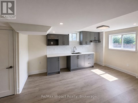 A kitchen area with a sink, cabinets, and a window.