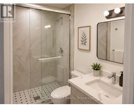 A bathroom with a white toilet, a sink, a mirror, and a shower with a glass door.