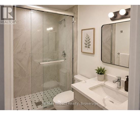 A bathroom with a white toilet, a sink, a mirror, and a shower with a glass door.