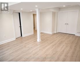 A spacious room with white walls and wooden flooring.