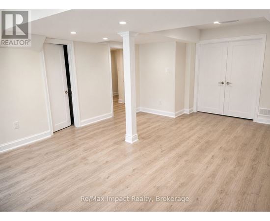 A spacious room with white walls and wooden flooring.