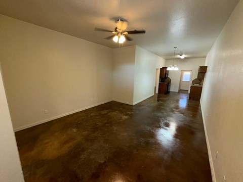 A room with a ceiling fan and a brown floor.