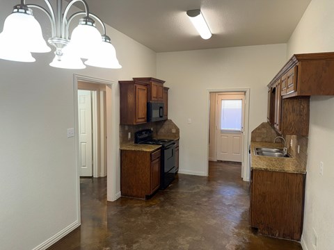A kitchen with brown cabinets and a granite counter.