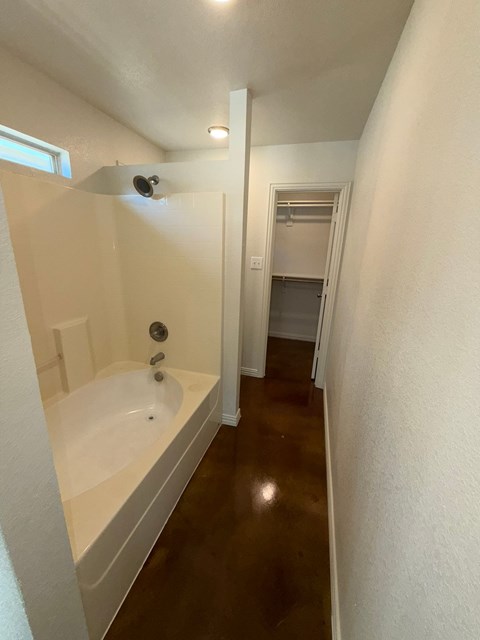 A white bathroom with a white tub and a window.