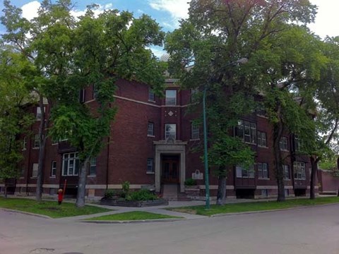 A red brick building with trees in front.