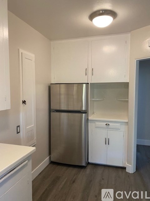 A kitchen with white cabinets and a stainless steel refrigerator.