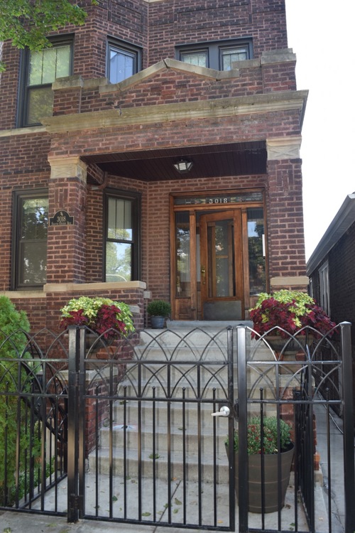 A brick house with a black gate and a wooden door.