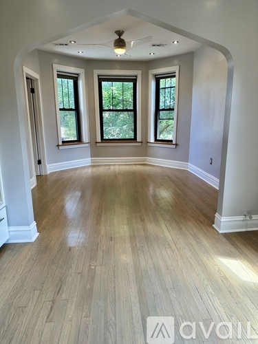 A spacious room with wooden floors and arched doorways.