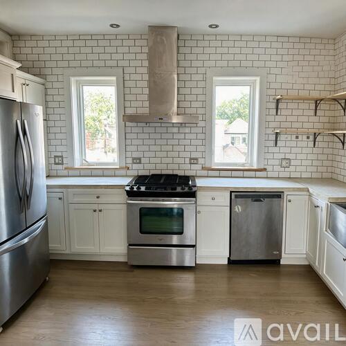 A kitchen with white cabinets and a stainless steel refrigerator.