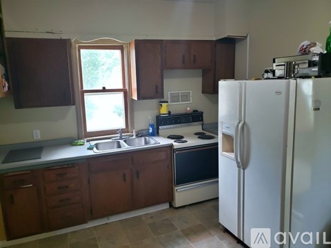 A kitchen with a white refrigerator, brown cabinets, and a window.