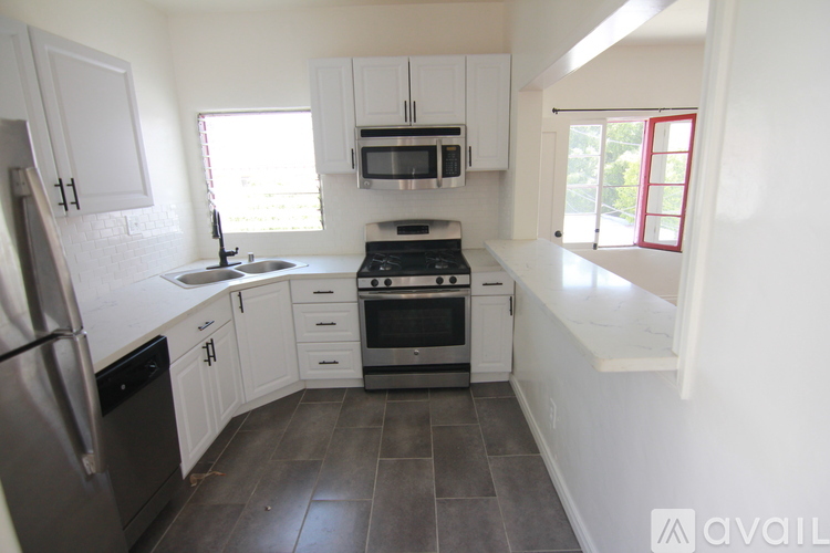 A kitchen with white cabinets and a black fridge.