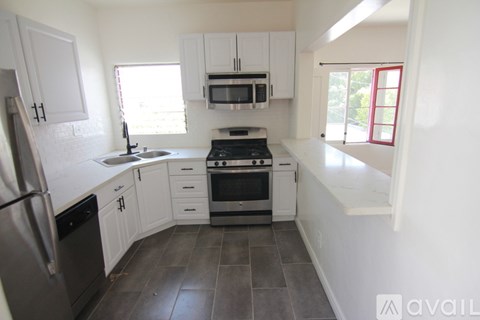 A kitchen with white cabinets and a black fridge.