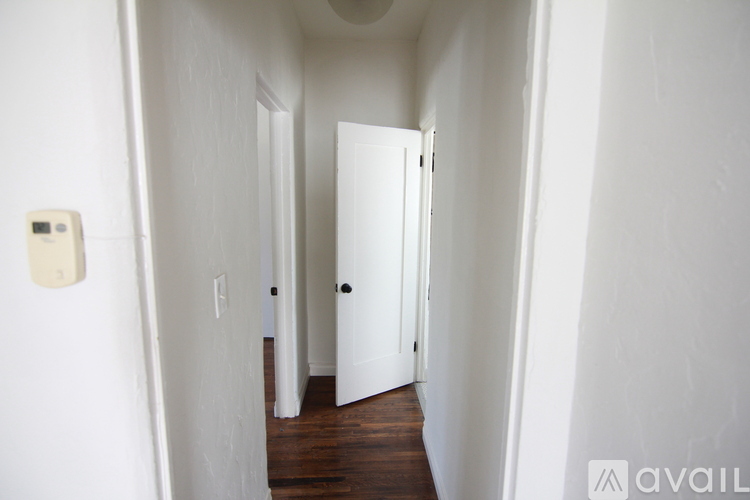 A hallway with a door and a light switch on the wall.