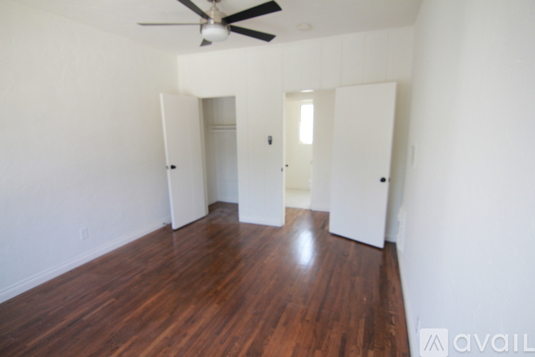 A room with a ceiling fan and wood flooring.