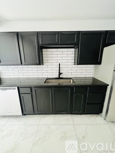 A kitchen with black cabinets and a white tiled backsplash.