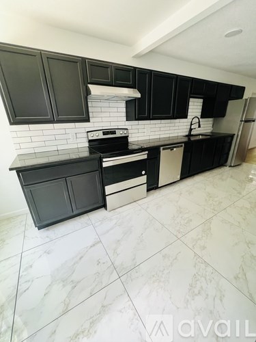 A kitchen with black cabinets and a white tile backsplash.