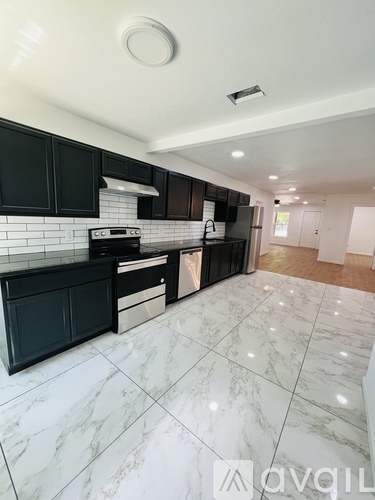 A kitchen with black cabinets and a marble floor.