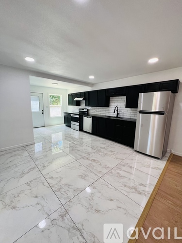A kitchen with white marble flooring and black cabinets.