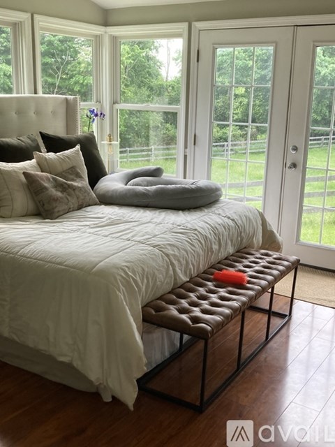 A bed with a white comforter and pillows is in a room with a glass door.