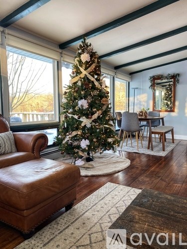 A living room with a Christmas tree and a brown leather chair.