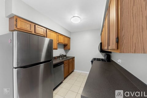 A kitchen with a stainless steel refrigerator and wooden cabinets.