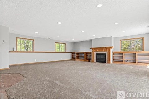 A spacious living room with a fireplace and built-in shelves.